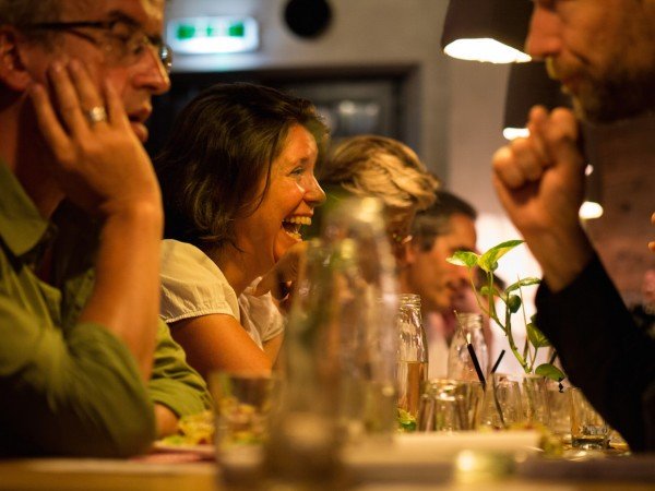 Mucbook: Rückblick auf das erste Erzähl-Mahl in München, lachende Frau am Tisch