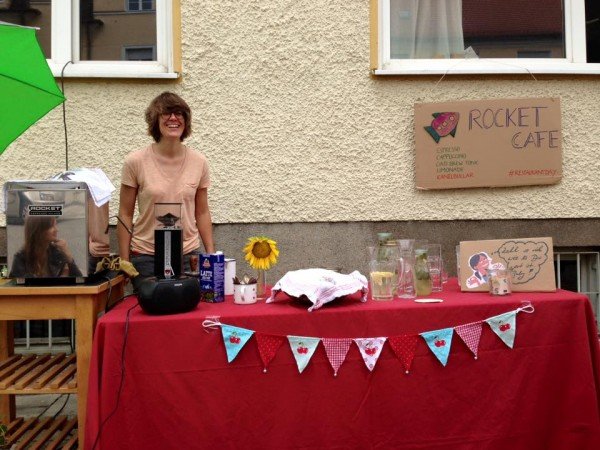 Mucbook: Rückblick Restaurant Day 16.8., Gastgeberin hinter Tisch mit Kaffeemaschine