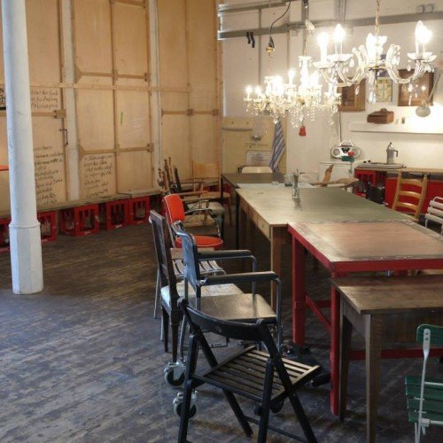 Mucbook: Laborküche im Kreativquartier mit geretteten Lebensmitteln am 31.10., Dinnertafel aus bunt zusammengewürfelten Tischen und Stühlen