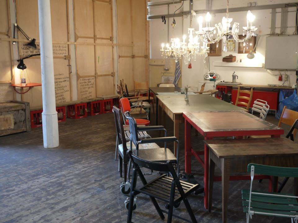 Mucbook: Laborküche im Kreativquartier mit geretteten Lebensmitteln am 31.10., Dinnertafel aus bunt zusammengewürfelten Tischen und Stühlen